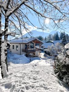 una casa en la nieve con suelo cubierto de nieve en Fuxbau Waldlounge en Ruhpolding