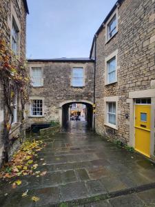 an alley between two brick buildings with a yellow door at Rose & Star Cottage in Frome