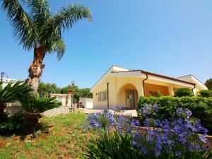 une maison avec un palmier et des fleurs violettes dans l'établissement Holiday home in Floridia with private pool, à Solarino