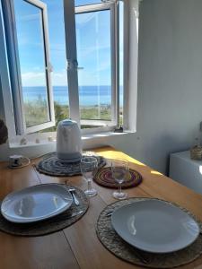 a table with plates and glasses on a table with windows at Blue View Terrace in Rodrigues Island
