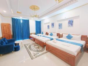a bedroom with two beds and a blue chair at Phuong Thuy Hotel in Can Tho