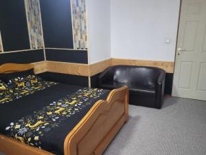 ein Schlafzimmer mit einem Bett und einem schwarzen Ledersessel in der Unterkunft Cabana Rosie in Vartop