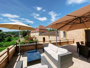 a patio with two umbrellas and a couch and chairs at L'Enea Terrasse in Saint-Cyprien