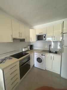 a kitchen with white cabinets and a washing machine at Sea view with direct access to boulevard in Puerto del Carmen