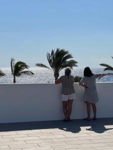 two women standing on a wall looking at a palm tree at Sea view with direct access to boulevard in Puerto del Carmen