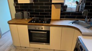 cocina con fogones horno de arriba junto a un fregadero en One Bedroom Apartment in Walsall Sleeps 4 FREE WIFI By Villazu en Bloxwich