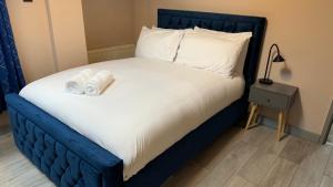 One Bedroom Apartment in Walsall Sleeps 4 FREE WIFI By Villazu في Bloxwich: سرير ازرق وعليه شرشف ووسائد بيضاء