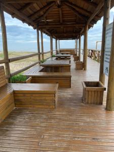 Edícula aconchegante 100m do Mar في Sombrio: سطح خشبي مع مقاعد وطاولات على الشاطئ