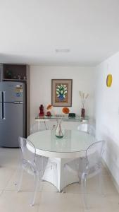 a white table and chairs in a kitchen with a refrigerator at Aconchegante Apartamento Beira-Mar (Ampla Varanda) in João Pessoa