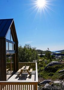 ein Haus mit einer Terrasse mit Sonne am Himmel in der Unterkunft Lofoten Cabins in Hopen