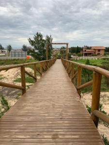 una pasarela de madera sobre una playa con un puente de madera en Edícula aconchegante 100m do Mar, en Sombrio