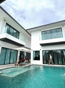 a man walking in front of a house with a swimming pool at Villa Coco in Thalang