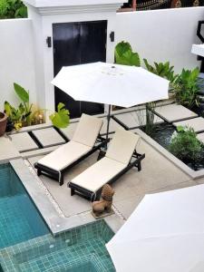 a patio with a table and chairs next to a pool at Villa Coco in Thalang