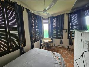 a bedroom with a bed and a table and windows at Hotel Quinto Sol in Mazunte