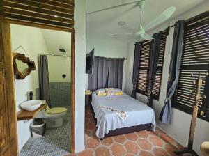 a bedroom with a bed and a toilet and a mirror at Hotel Quinto Sol in Mazunte