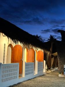 uma casa com portas de madeira e um telhado de palha em Hiraya Baler Beachfront Cabanas em Baler