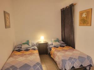 two twin beds in a room with a lamp at Apartamento funcional en residencial con piscina en inmejorable ubicación en centro de la isla in Caleta De Fuste