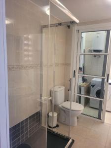 a bathroom with a toilet and a glass shower at Apartamento funcional en residencial con piscina en inmejorable ubicación en centro de la isla in Caleta De Fuste