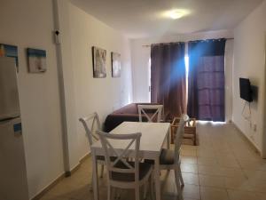 a living room with a table and chairs and a couch at Apartamento funcional en residencial con piscina en inmejorable ubicación en centro de la isla in Caleta De Fuste