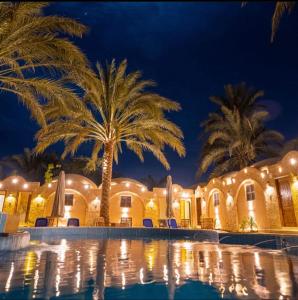 un complexe avec des palmiers et une piscine ouverte la nuit dans l'établissement Siwa Palace Lodge, à Siwa
