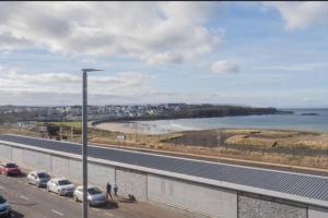 a road with cars parked next to a beach at Modern appartment with sea views in Portrush