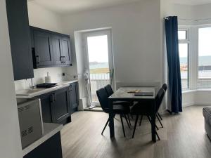 a kitchen and dining room with a table and chairs at Modern apartment with sea views in Portrush