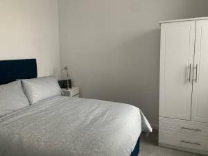a bedroom with a bed and a white cabinet at Modern appartment with sea views in Portrush