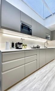 cocina con armarios blancos y microondas en Designer Guesthouse Pulau Tikus & Gurney Drive, Georgetown, Penang en George Town