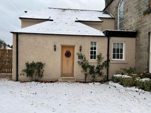 a house with a door in the snow at Quaint self contained cottage near Edinburgh. in Loanhead