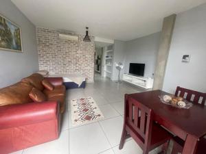 Wild olive B في ويندهوك: غرفة معيشة مع أريكة حمراء وطاولة