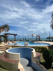 una piscina con sillas y vistas al océano en Apto 2 quartos - Condomínio Frente Mar en Beberibe