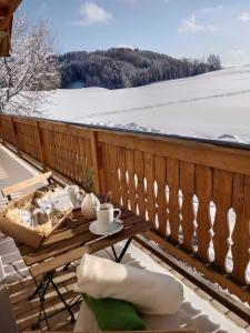 einen Tisch auf einem Balkon mit Schnee auf dem Boden in der Unterkunft Biohof-Feichtinger in Zell am Moos