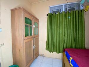 Harry & Mimin Homestay في جورونتالو: غرفة بسرير وستارة خضراء