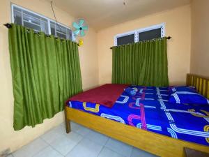 Harry & Mimin Homestay في جورونتالو: غرفة نوم بسرير مع ستائر خضراء