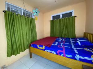Harry & Mimin Homestay في جورونتالو: غرفة نوم بسرير مع ستائر خضراء