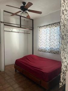 a bedroom with a red bed and a ceiling fan at Departamento a 10min Cd Universitaria in Monterrey