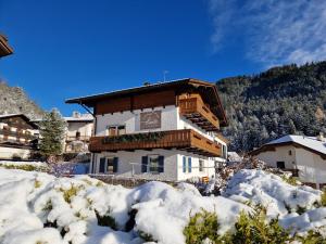 um edifício com neve em frente em Haus Herta B&B em Nova Levante