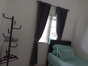 a bedroom with a window with black curtains and a bed at Homey Homestay at Citraland Cirebon in Cirebon