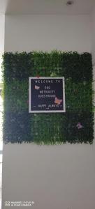 a sign on a wall with plants and flowers at D&Q METROCITY GUESTHOUSE in Kuching