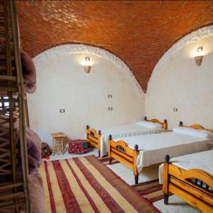 Cette chambre comprend 2 lits et un mur en briques. dans l'établissement Siwa Palace Lodge, à Siwa
