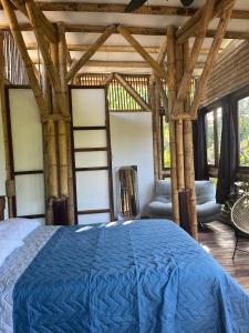 a bedroom with a blue bed in a room with windows at Tayrona Juancho's House Hostel & Coworking in Los Naranjos