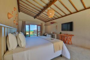 a bedroom with a large white bed and a television at MONAN BOUTIQUE HOTEL in Pôrto de Pedras