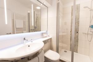 a white bathroom with a sink and a shower at Hotel Bavaria Oldenburg in Oldenburg