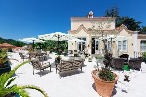 eine Terrasse mit Stühlen, Tischen und Sonnenschirmen in der Unterkunft Hotel Nova Sintra - Adults only in Sintra