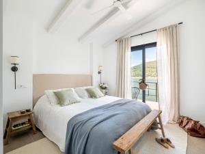 a white bedroom with a large bed and a window at Casa junto al Pantano de Burguillo in El Tiemblo