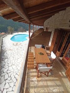 een patio met een tafel en stoelen en een zwembad bij Helmos Mountain Retreat in Zarouhla