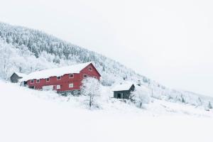 a red barn with snow on the side of a mountain at Hafjell Farmhouse in Øyer