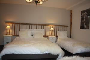 a bedroom with two beds with white sheets and lamps at Les gîtes "Cœur de ferme" in Celles