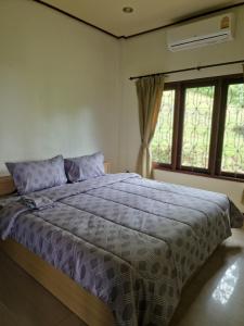 a bedroom with a bed with purple comforter and a window at Bungalow vue mer in Amphoe Koksamui