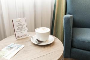 eine Tasse Kaffee auf einem Tisch neben einem Stuhl in der Unterkunft Hotel Bavaria Oldenburg in Oldenburg